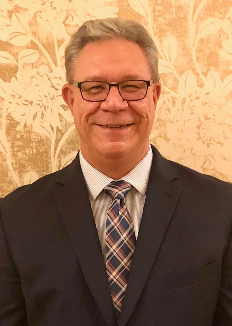 A man in suit and tie smiling for the camera.